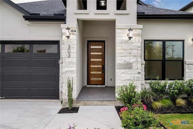 303 W Lane Ave, Manor, TX 78653 - entrance to property with stone siding, a shingled roof, stucco siding, and a garage