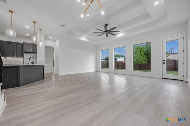 303 W Lane Ave, Manor, TX 78653 - unfurnished living room featuring recessed lighting, a ceiling fan, light wood-style floors, and a tray ceiling
