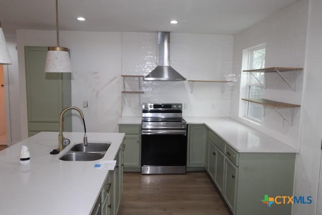 kitchen with green cabinetry, stainless steel electric range, sink, wall chimney exhaust hood, and pendant lighting