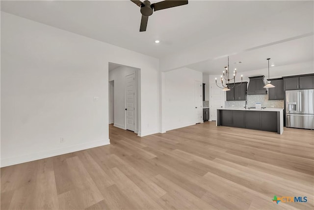 unfurnished living room with recessed lighting, baseboards, light wood finished floors, and ceiling fan with notable chandelier