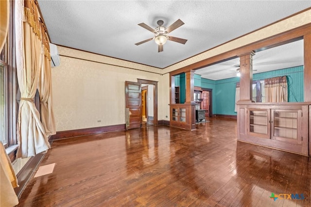 9 S Milam St, Rogers, TX 76569 - unfurnished living room with a textured ceiling, ceiling fan, wood-type flooring, and decorative columns
