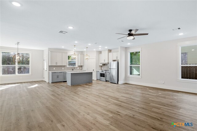 unfurnished living room featuring light wood-type flooring, a healthy amount of sunlight, and ceiling fan