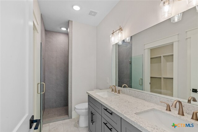 bathroom with vanity, a shower with door, tile patterned flooring, and toilet