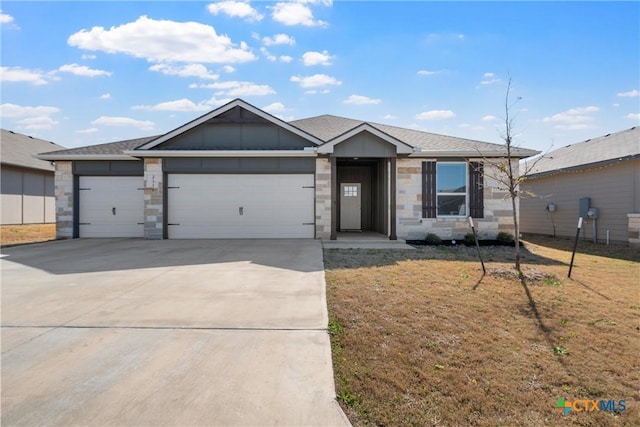 ranch-style house with a front yard, driveway, roof with shingles, an attached garage, and stone siding