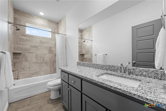 full bath featuring wood finished floors, toilet, shower / bath combo, and vanity