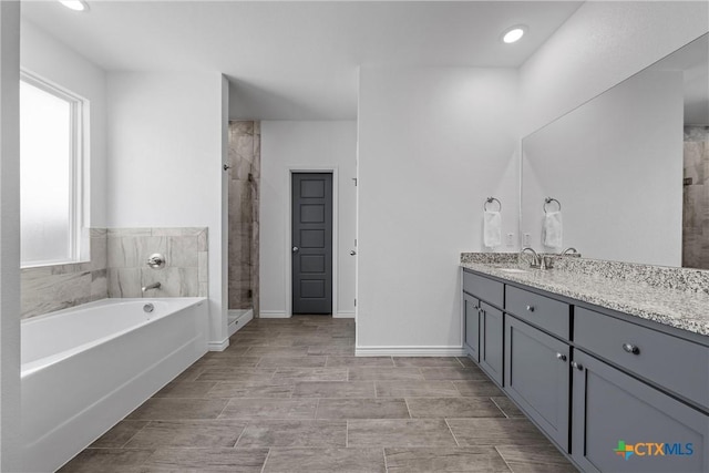 full bathroom with baseboards, a garden tub, a shower stall, and vanity