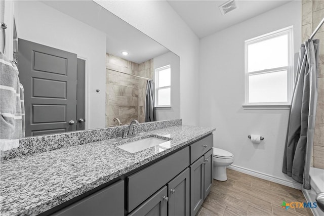 bathroom featuring visible vents, toilet, a tile shower, baseboards, and vanity