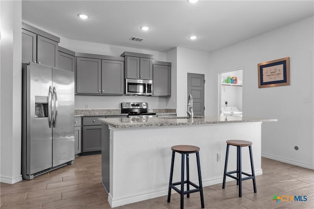 kitchen featuring visible vents, wood tiled floor, gray cabinets, appliances with stainless steel finishes, and a sink