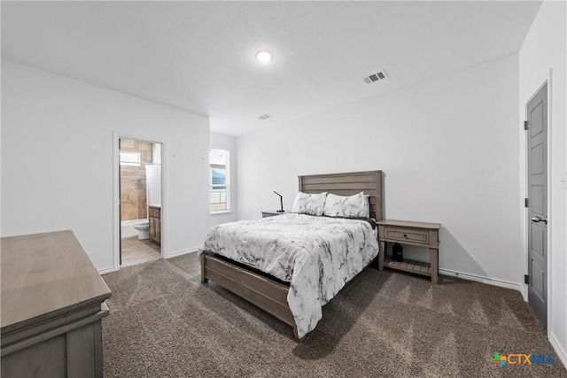 carpeted bedroom with visible vents, ensuite bathroom, and baseboards