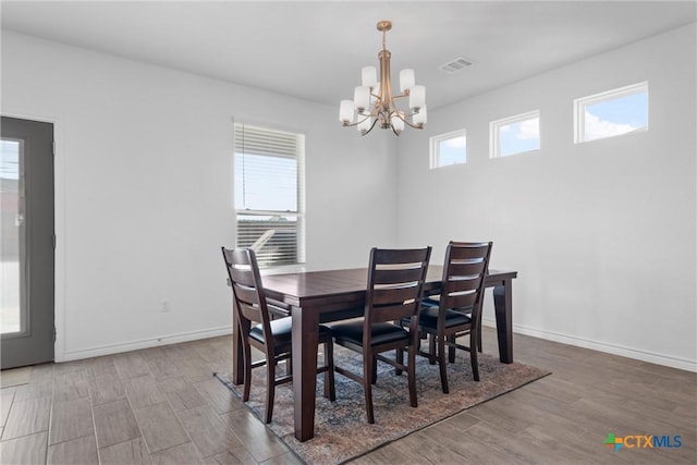 dining area with a notable chandelier, wood finished floors, visible vents, and baseboards