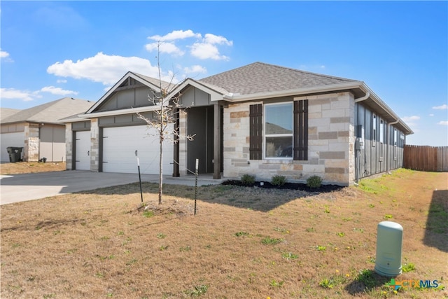 view of front facade with stone siding, an attached garage, driveway, and a front yard