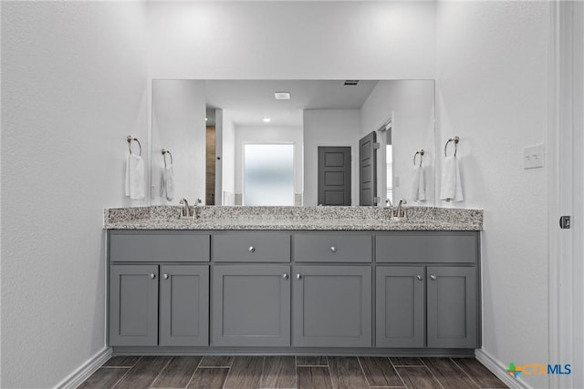 bathroom featuring a sink, baseboards, wood tiled floor, and double vanity