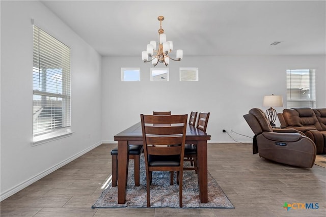 dining room featuring visible vents, baseboards, an inviting chandelier, and wood finished floors