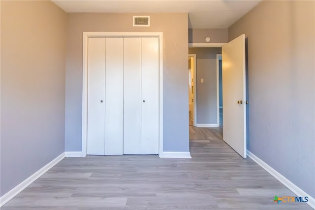 unfurnished bedroom with light wood-type flooring and a closet