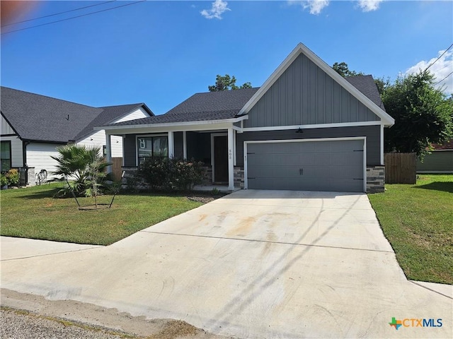 505 E Convent St, Victoria, TX 77901 - view of front of home featuring board and batten siding, stone siding, an attached garage, a front yard, and driveway