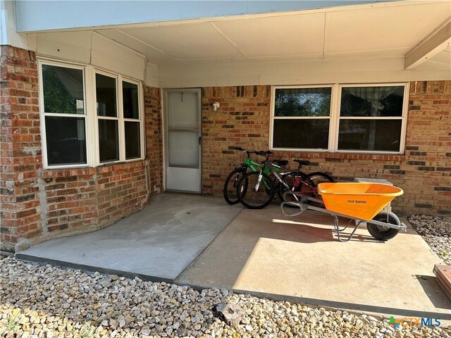 rear view of property with a lawn, brick siding, central AC, a patio, and a shingled roof