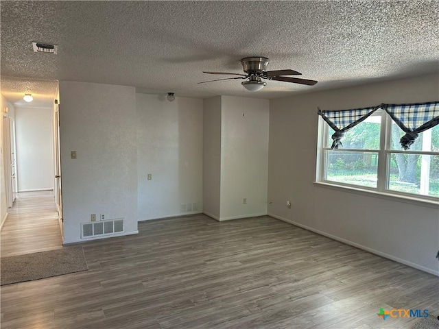 spare room featuring a ceiling fan, visible vents, and wood finished floors