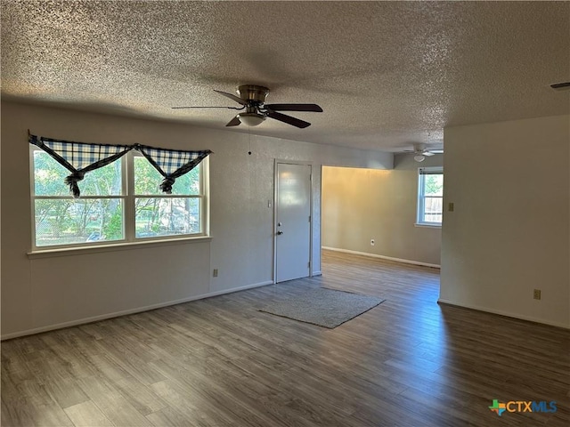 spare room with a ceiling fan, a textured ceiling, visible vents, wood finished floors, and baseboards