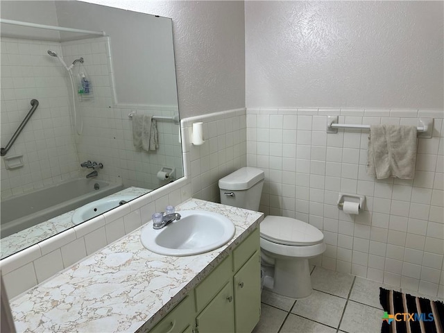 bathroom featuring shower / bathing tub combination, tile walls, vanity, toilet, and a textured wall