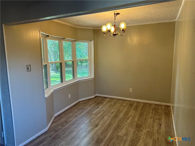 unfurnished room with an inviting chandelier, a textured ceiling, crown molding, and wood finished floors