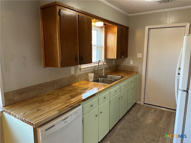 kitchen featuring crown molding, a sink, white appliances, a textured ceiling, and wood finished floors