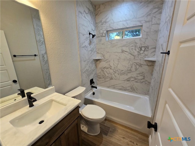 full bathroom featuring vanity, wood-type flooring, tiled shower / bath combo, and toilet