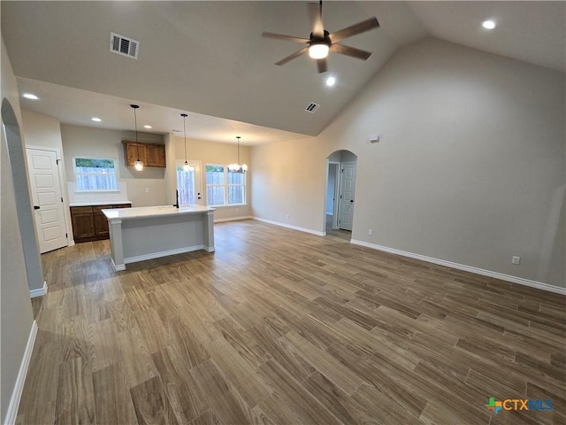 kitchen with ceiling fan with notable chandelier, an island with sink, pendant lighting, and dark hardwood / wood-style floors