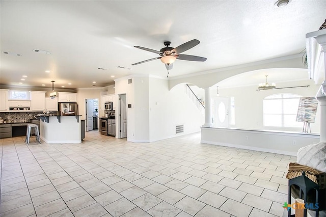 living area featuring visible vents, arched walkways, ceiling fan, ornamental molding, and light tile patterned flooring