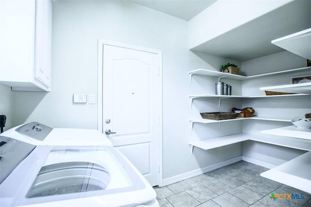 clothes washing area with cabinet space, baseboards, and washing machine and clothes dryer