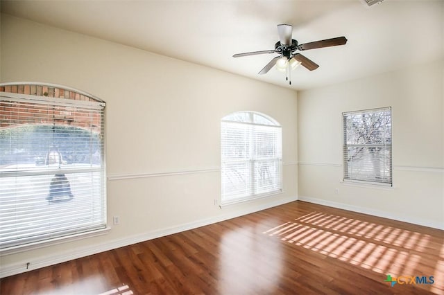 unfurnished room with ceiling fan, wood finished floors, and baseboards