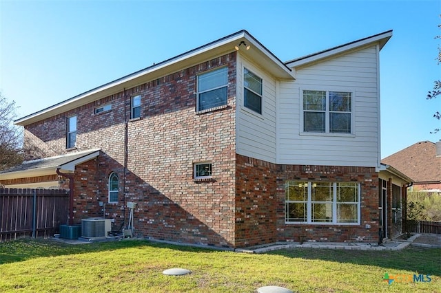 rear view of property with a yard, brick siding, central AC, and fence