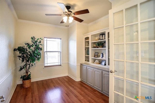 interior space featuring dark wood-style floors, ornamental molding, baseboards, and a ceiling fan