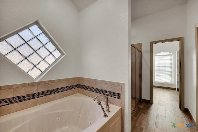 bathroom with a relaxing tiled tub and vaulted ceiling