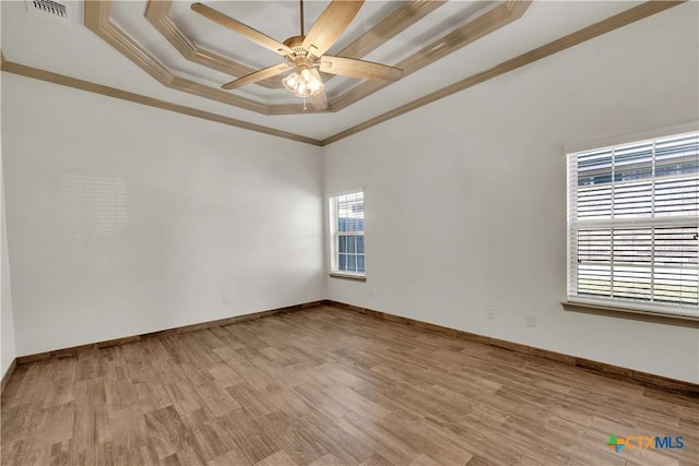 unfurnished room featuring a raised ceiling, crown molding, ceiling fan, and light wood-type flooring