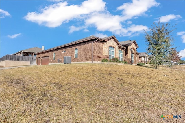 back of house with a yard, central AC unit, and a garage