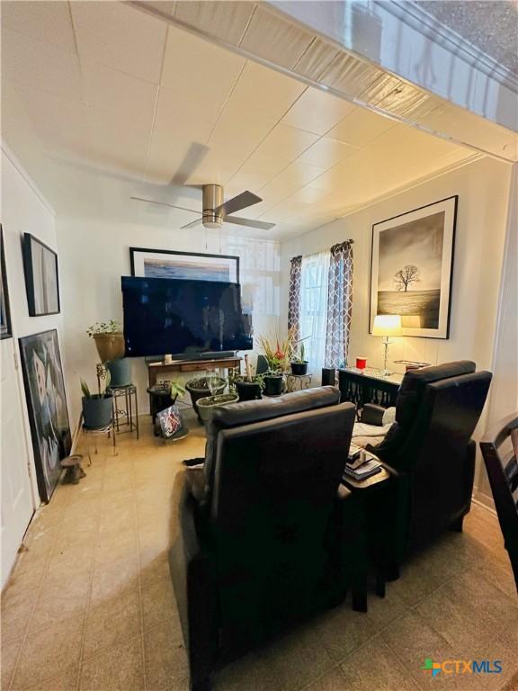 living area with light tile patterned floors and ceiling fan