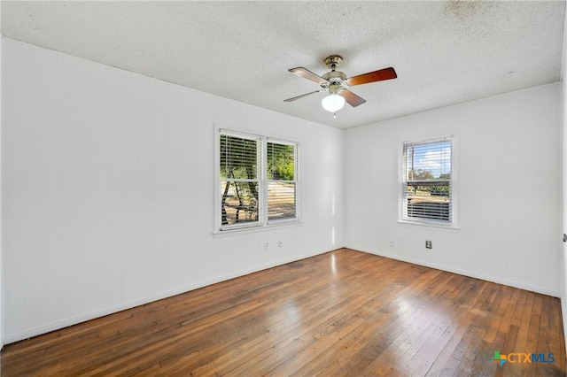 unfurnished room featuring dark hardwood / wood-style flooring, a textured ceiling, and a wealth of natural light