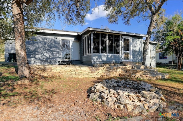 rear view of house featuring a sunroom and a fire pit