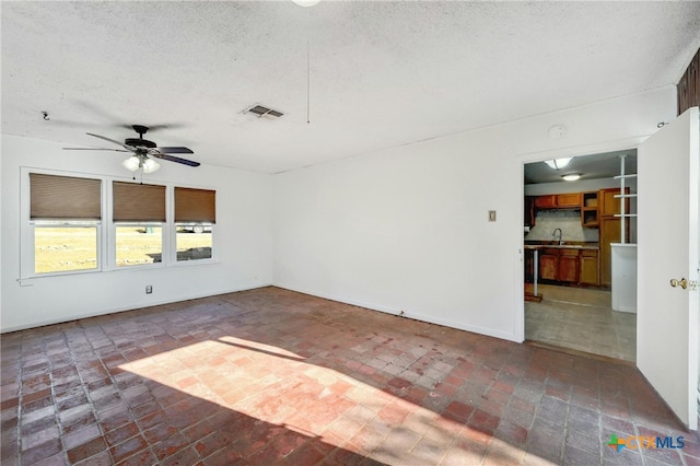 spare room with a textured ceiling, ceiling fan, and sink