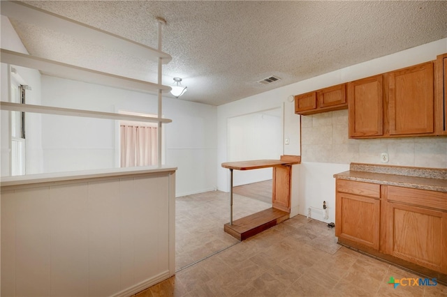 kitchen with a textured ceiling and tasteful backsplash