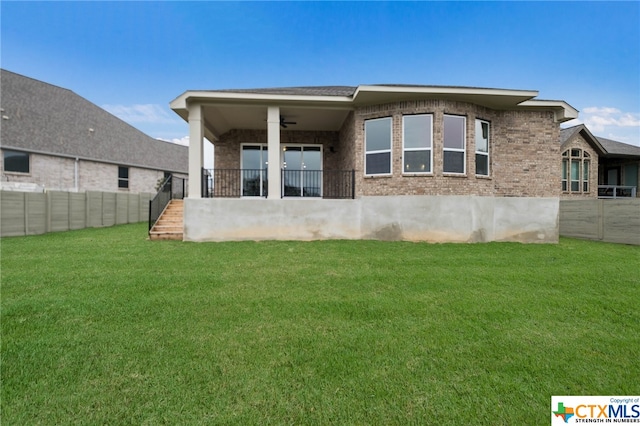 rear view of property with ceiling fan and a lawn