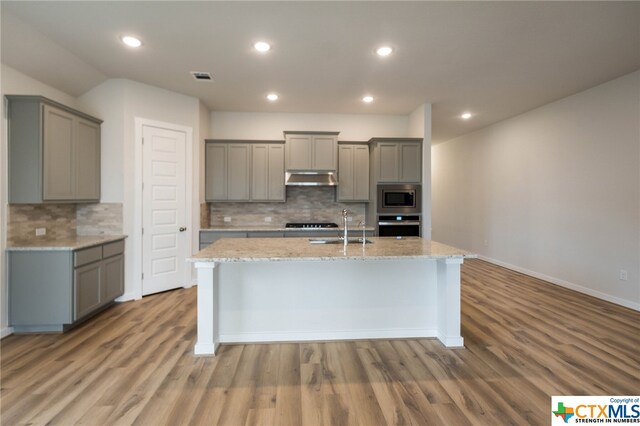 kitchen with gray cabinetry, wood-type flooring, backsplash, appliances with stainless steel finishes, and sink