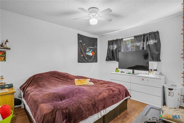 bedroom featuring ceiling fan, light hardwood / wood-style flooring, and a textured ceiling