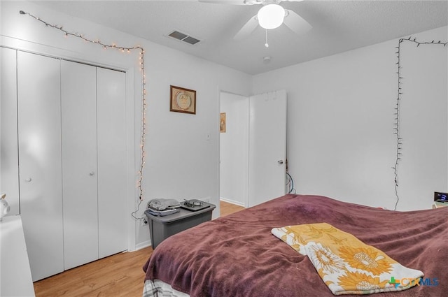 bedroom with a closet, ceiling fan, light hardwood / wood-style flooring, and a textured ceiling