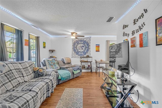 living room featuring a textured ceiling, light hardwood / wood-style flooring, and ceiling fan