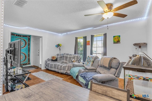 living room with ceiling fan, hardwood / wood-style floors, and a textured ceiling