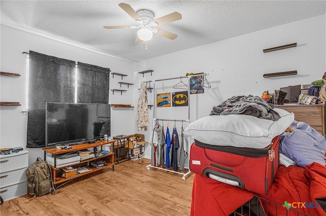 bedroom with ceiling fan, hardwood / wood-style floors, and a textured ceiling