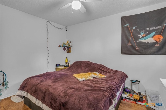 bedroom with ceiling fan, wood-type flooring, and a textured ceiling