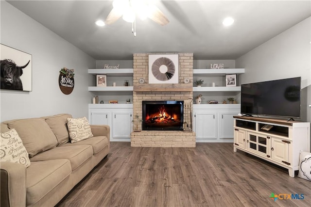 living room with ceiling fan, dark hardwood / wood-style flooring, and a brick fireplace