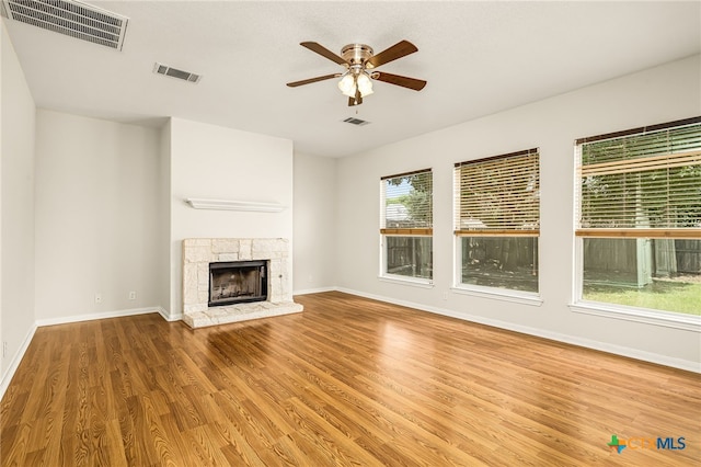 unfurnished living room with ceiling fan, wood-type flooring, and a fireplace